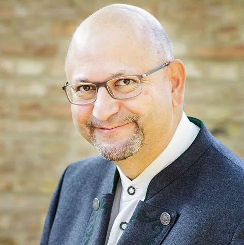 Lächelnder Mann mit Brille und Ziegenbart in Tracht.