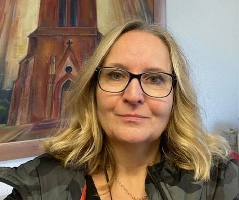 Frau mit Brille vor einem Kirchengemälde.