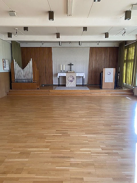 Leerer Kirchenraum mit Altar, Kreuz und Orgel.