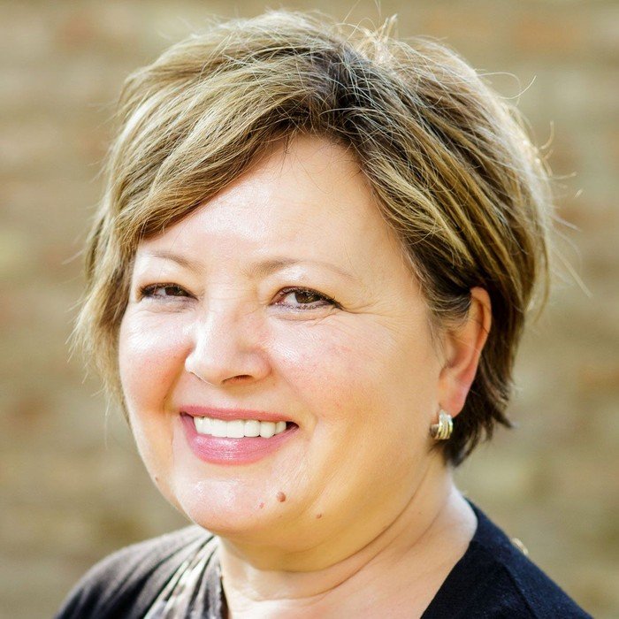 Eine lächelnde Frau mit kurzen, hellbraunen Haaren.